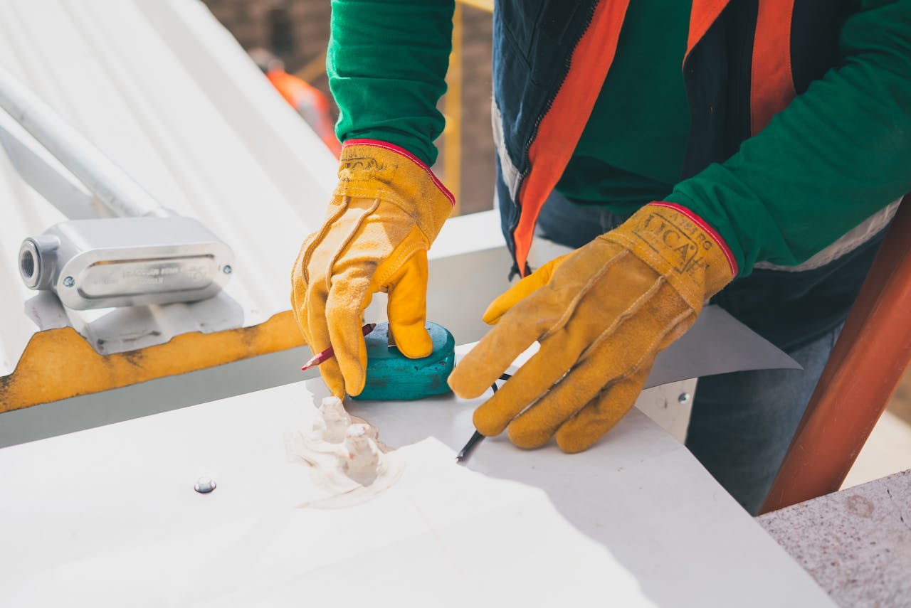 our-services-1 Electrician measuring on rooftop, wearing protective gloves, during daylight.